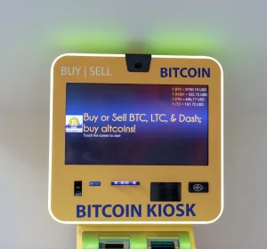 Bitcoin kiosk in a public indoor space displaying buy and sell options for bitcoin and altcoins.