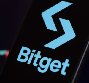 Bitget logo on smartphone screen with blurred trading chart background