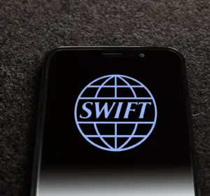 Smartphone displaying the SWIFT logo on a dark screen against a textured black background.