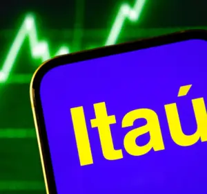Smartphone displaying the Itaú logo in front of a green financial market chart.
