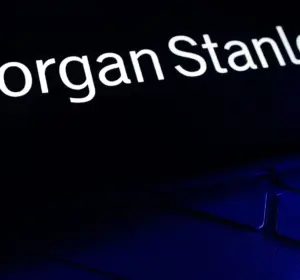 Smartphone displaying the Morgan Stanley logo in white text on a black screen, resting on a blue-lit keyboard