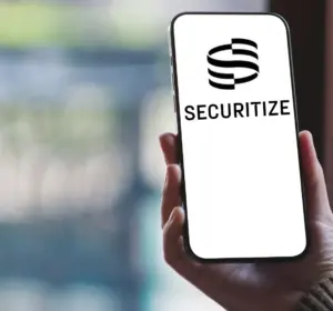 Hand holding a smartphone displaying the Securitize logo against a blurred background