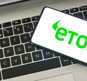 Smartphone displaying the green eToro logo resting diagonally on a laptop keyboard