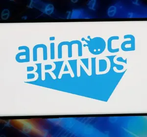 Smartphone displaying the Animoca Brands logo against a digital background of binary code and data graphics.
