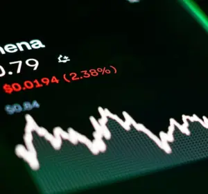 Smartphone displaying Ethena price data and a market chart under green lighting on a trading interface.