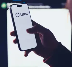 Grok AI logo displayed on a smartphone held in front of a blurred digital interface